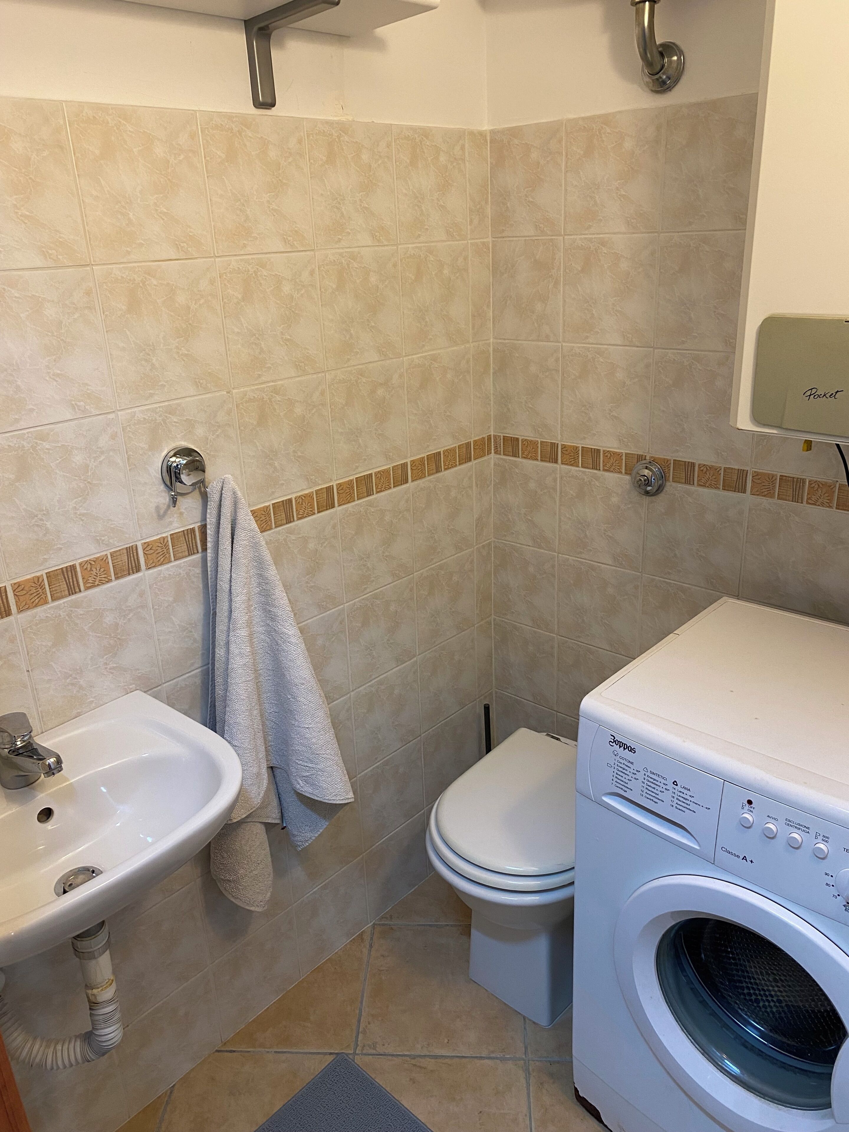 A bathroom with a sink, toilet, and washing machine.