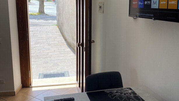 Une pièce dans laquelle un téléviseur est fixé au mur et qui diffuse différents services de streaming. On y trouve une table avec une télécommande et des sets de table décoratifs.