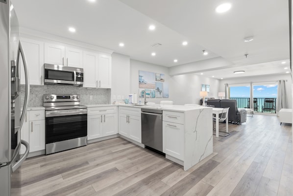 Una cocina moderna con armarios blancos, electrodomésticos de acero inoxidable y piso de madera.