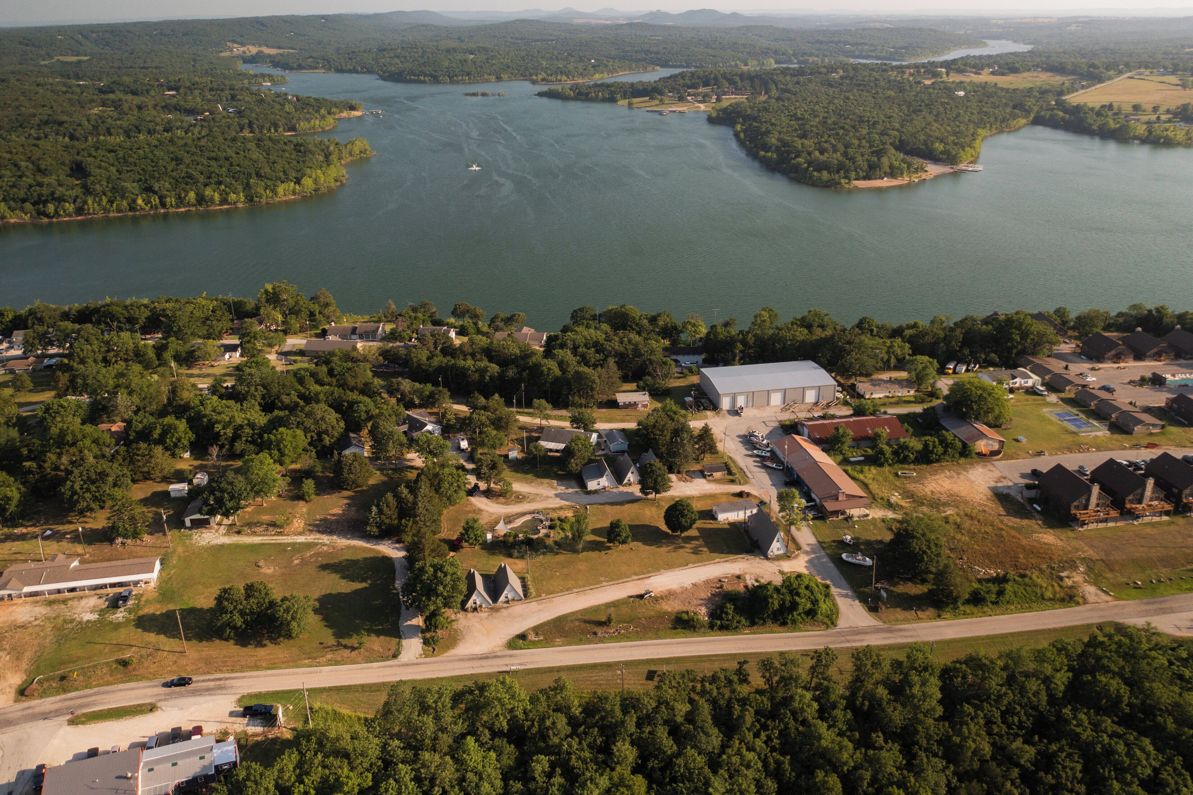 An aerial view of a residential area with houses, a large body of water, and a road.