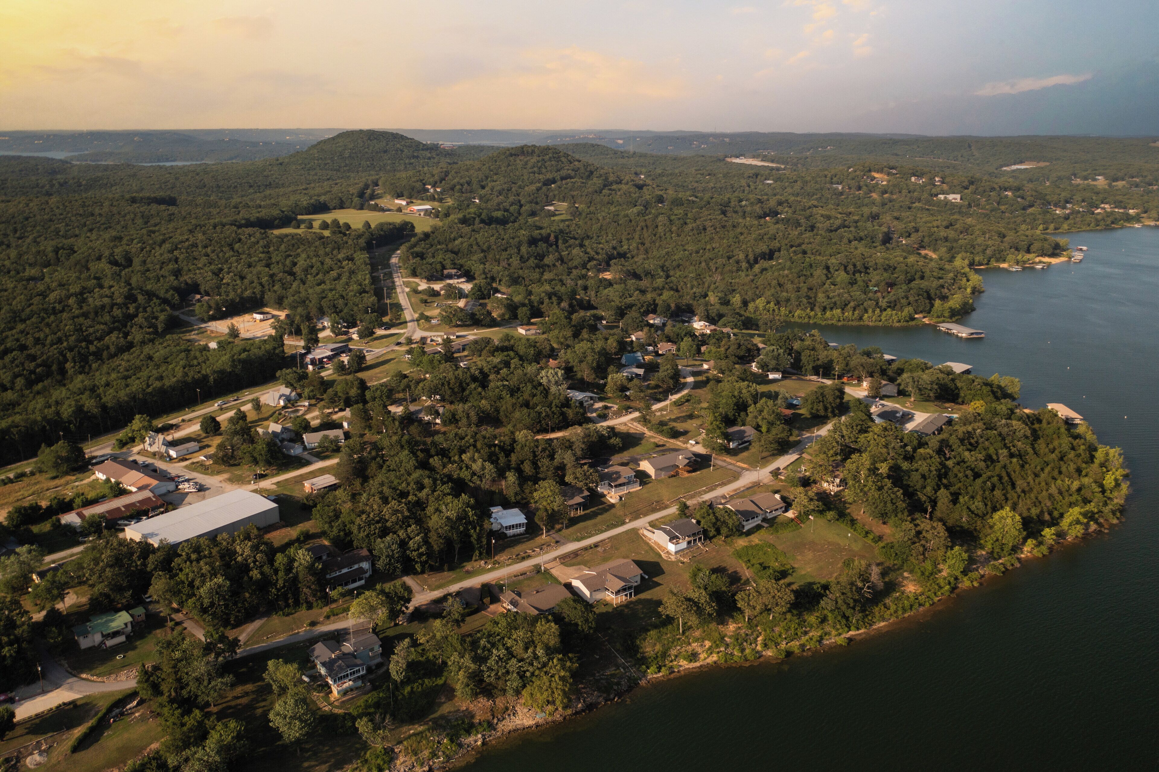 An aerial view of a lakeside residential area with houses, roads, and a large building.