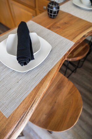 Una mesa de madera con un plato blanco y una servilleta negra.
