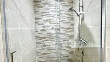 A shower area with a glass door, a showerhead, and a handheld shower attachment.