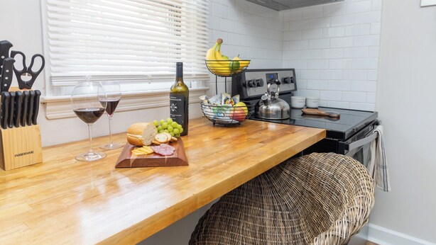 A kitchen with a wooden countertop, a wine bottle, a kettle, and a fruit bowl. - 2 bed/1 ba-across f/Coliseum/GAC (Greensboro)