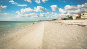 Ein Strand mit blauem Himmel und Fußabdrücken im Sand.