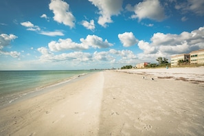 Ein Strand mit blauem Himmel und Fußabdrücken im Sand.