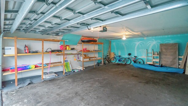 Un garaje con estanterías metálicas, bicicletas y un kayak.