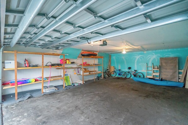 A garage with metal shelving units, bicycles, and a kayak. - Seashell 19 by Distinctive Beach Rentals (Indian Shores)