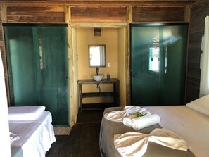Une chambre avec deux lits, une petite salle de bain avec un lavabo et un miroir.