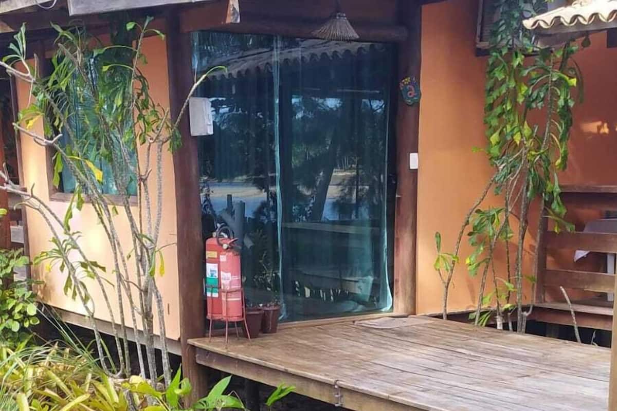 Un escalier en bois mène à une porte en verre, qui est entourée de plantes en pot et d’un extincteur.
