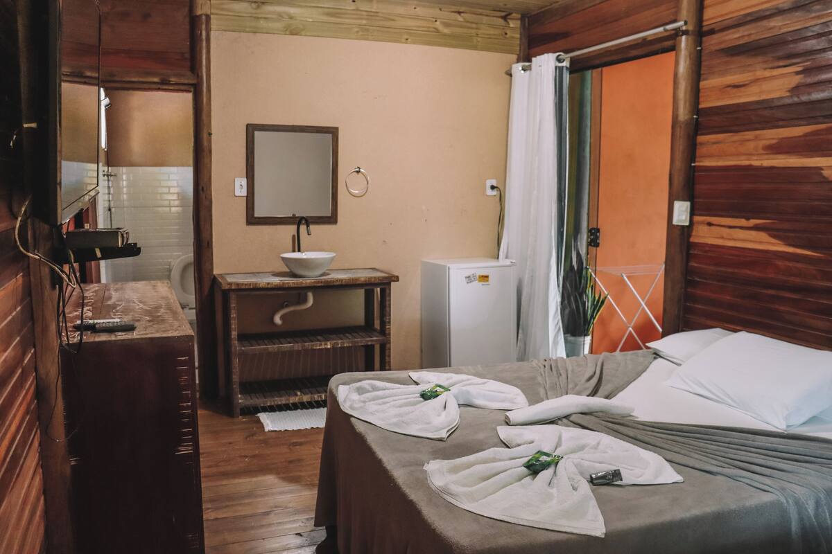 Une pièce de style cabane en bois, avec un lit, un petit lavabo et un miroir.
