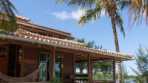 A wooden house with a tiled roof, a porch, and a hammock. - Pôr do Sol Eco Suítes (Maraú)