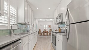 Una cocina moderna con armarios blancos, electrodomésticos de acero inoxidable y un salpicadero de azulejos.