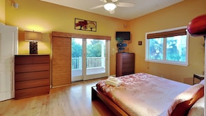 Un dormitorio con cama, cómoda, televisor y ventana.