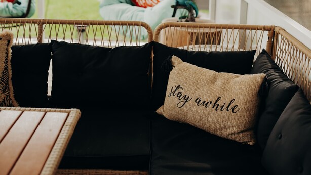 A covered patio area with wicker furniture, including a sofa and chairs, and a wooden table. - Pool, Hot Tub, Enclosed Patio, Close to Everything-A Million Memories (St. Augustine)