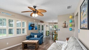 A spacious living room with a ceiling fan, a blue sofa, a white sofa, and a wooden coffee table. - Pool, Hot Tub, Enclosed Patio, Close to Everything-A Million Memories (St. Augustine)
