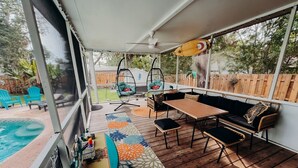 An outdoor patio with a pool, a wooden deck, a hanging chair, a sofa, and a table. - Pool, Hot Tub, Enclosed Patio, Close to Everything-A Million Memories (St. Augustine)