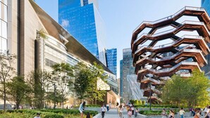 Een modern stadsplein met eigentijdse architectuur, waaronder een opvallende hexagonale structuur en glazen gebouwen.
