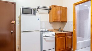 Een kleine keuken met een koelkast, magnetron, kookplaat en spoelbak.