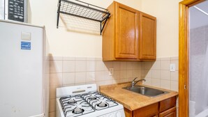 Een keuken met een witte kookplaat, houten kastjes, een spoelbak en een magnetron.