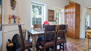 A dining area with a wooden table and chairs, a fireplace, and a large wooden door. - Siete Caballos by Kokopelli Property Management (Santa Fe)