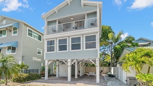 A two-story house with a balcony, a covered patio, and a number 18 sign. - Sunset Beach House by Distinctive Beach Rentals (Treasure Island)