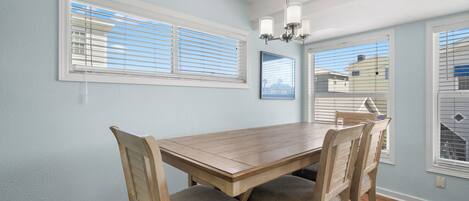 Un comedor con una mesa y sillas de madera, paredes azul claro y una araña.