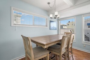 A dining area with a wooden table and chairs, light blue walls, and a chandelier.