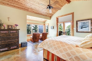 A bedroom with a large bed, wooden ceiling, and a view of the outdoors.