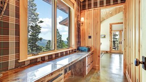A wooden interior with a large window, a built-in bench, and a view of trees and mountains.