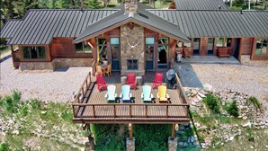 A lodge with a stone facade, a covered deck with Adirondack chairs, and a stone fireplace.
