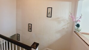 A staircase with a wooden handrail and white balusters, leading to a landing with a white textured wall. - Enjoy this Cozy Brooklyn Room with Parking & Shared Kitchen & Bathroom (Brooklyn)