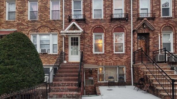 A multi-story brick building with a central entrance, a small porch, and a staircase leading to the upper floors. - Enjoy this Cozy Brooklyn Room with Parking & Shared Kitchen & Bathroom (Brooklyn)