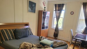 A bedroom with a bed, a wooden headboard, a cabinet, a chair, and a window with curtains. - Enjoy this Cozy Brooklyn Room with Parking & Shared Kitchen & Bathroom (Brooklyn)