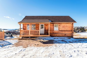 A wooden cabin with a porch, a door, and windows. - Oso Lucky Lodge • Hot Tub • Walk to Casinos (Cripple Creek)