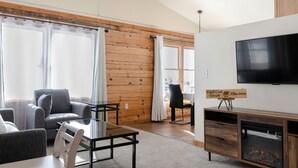 Un salon moderne avec une cheminée, des lambris en bois et un grand téléviseur.
