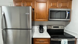Una cocina con un refrigerador de acero inoxidable, un microondas, un horno y una cafetera.