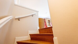 A staircase with wooden steps and white handrails, leading to a landing with a bookshelf. - Haus Raanwai - Wattblick. Natur. Familie. - Rhr/3a (Sylt)