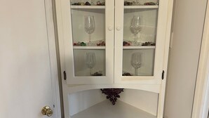 A white cabinet with two glass doors and a lower section with two solid doors.