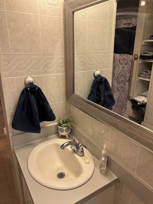 Baño con lavamanos, espejo y toallero.