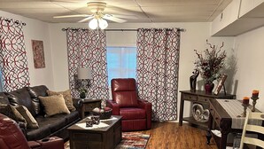 A living room with a leather sofa, a red recliner, a wooden coffee table, and a patterned rug.