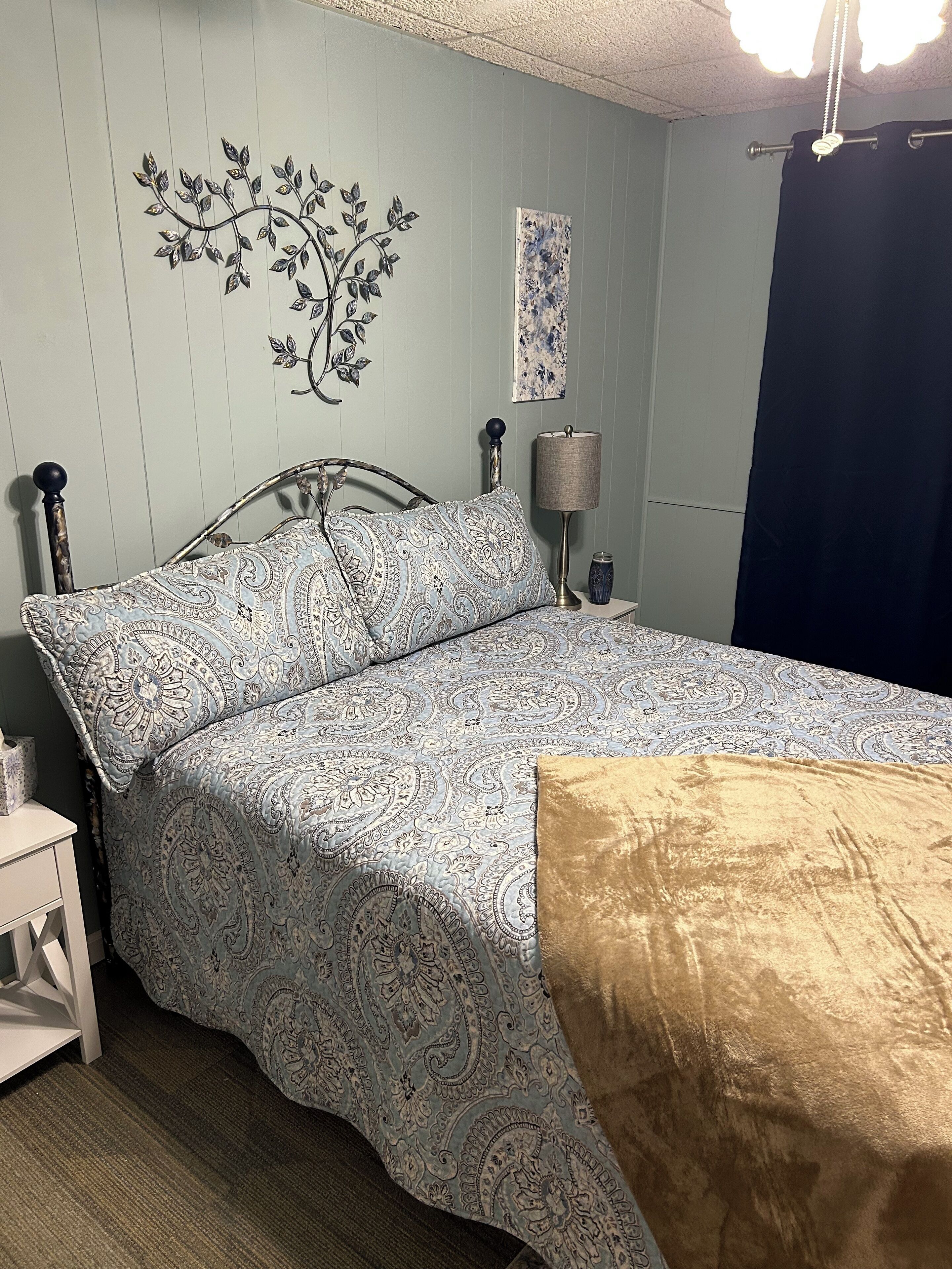 Una camera da letto con un letto, un comodino, una lampada e un elemento decorativo al muro.