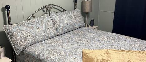 Una camera da letto con un letto, un comodino, una lampada e un elemento decorativo al muro.