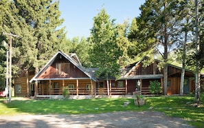 Ein rustikales Blockhaus mit Veranda, umgeben von dichtem Wald.