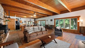 Un vaste espace de vie doté d’un plafond en bois, d’une cheminée, d’un canapé, d’une table basse et d’une grande fenêtre offrant une vue sur l’extérieur.