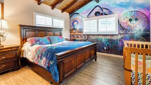 Un dormitorio con una cama grande, cabecera de madera y un mural de noria y Mickey Mouse.