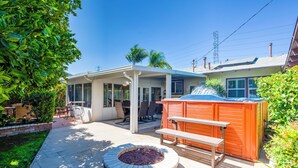 Patio trasero con jacuzzi, fogata y mobiliario exterior.