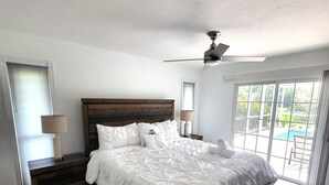 A spacious bedroom with a large bed, wooden headboard, and a ceiling fan. - Emerald House : Free Amazing Heated Pool !!!!! (Bradenton)