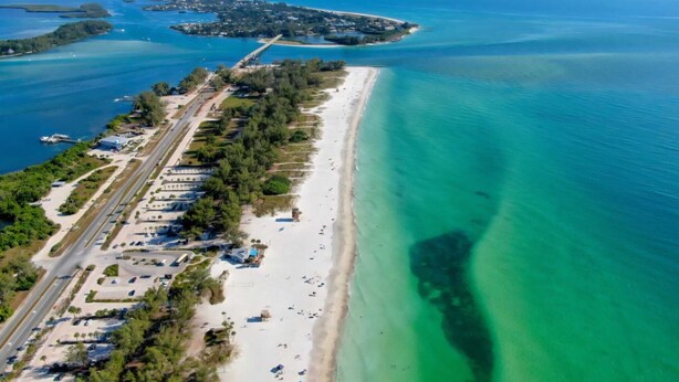 An aerial view of a coastal area with a long stretch of beach, a road parallel to the shore, and a small island in the distance. - Emerald House : Free Amazing Heated Pool !!!!! (Bradenton)