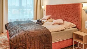 A hotel room with a bed, a nightstand, and a window with curtains.